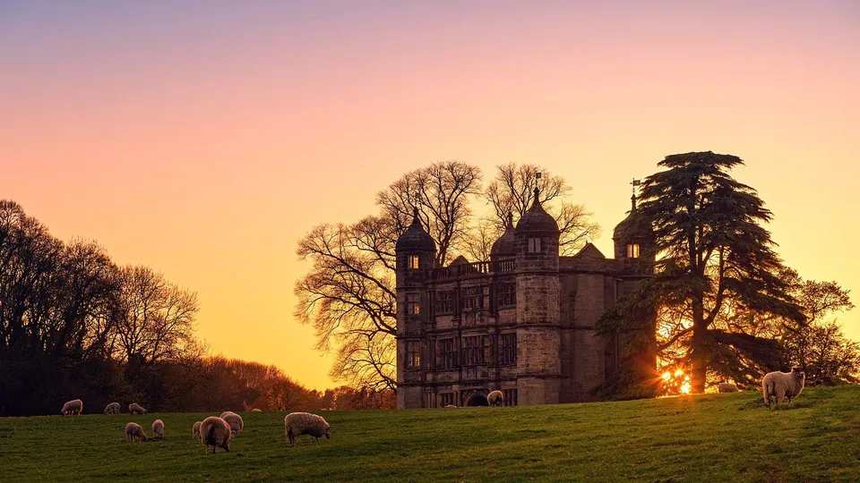 An English gatehouse at sunset, with sheep grazing in front