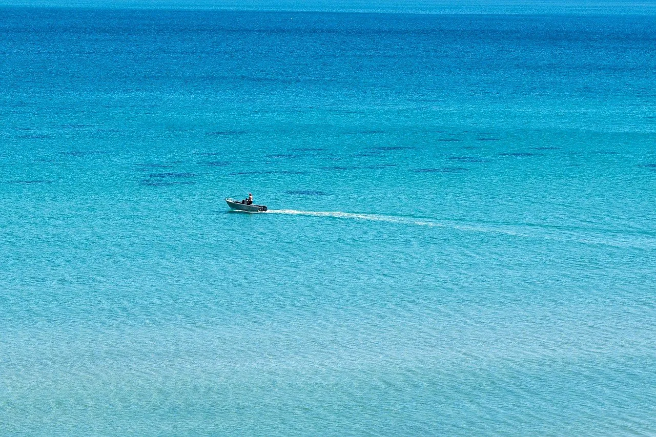 A single boat crossing clear turquoise water